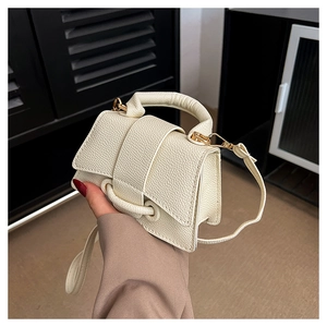 Close-up of off-white crossbody bag showing lychee pattern texture and gold hardware