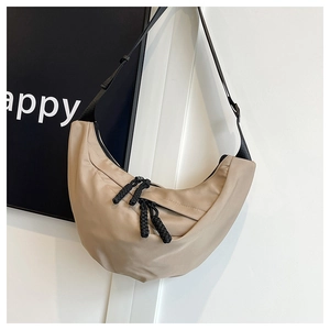 Dettaglio della borsa a mezzaluna beige con tracolla nera regolabile e tirazip in corda