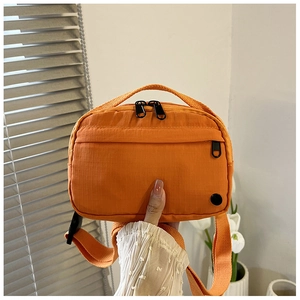 Detail of orange nylon crossbody bag with ripstop texture and adjustable shoulder strap