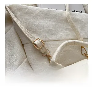 Detail of light gold adjustable buckle on white tweed and lychee leather shoulder strap
