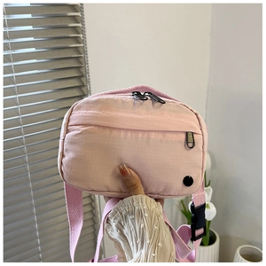 Detail of pink nylon crossbody bag featuring grid texture and durable plastic buckle