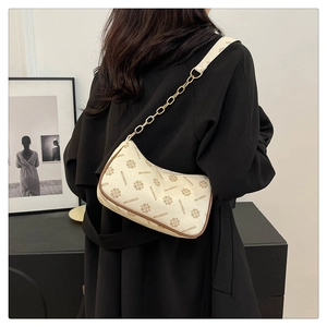 Detail of a vintage crescent shoulder bag with monogram print and gold chain strap
