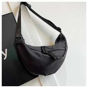 Dettaglio borsa a mezzaluna in nylon nero con nodi intrecciati e ampia tracolla sportiva
