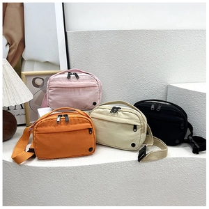 Close-up of lightweight nylon crossbody bags in four colors on a display stand