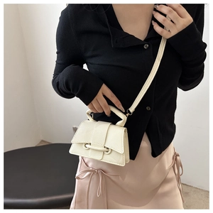 Detail of a mini cream white crossbody bag with lychee texture and flap cover design