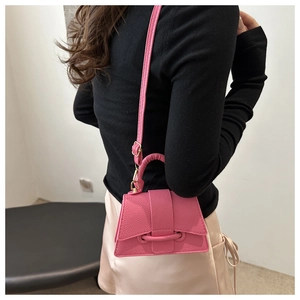 Close-up of pink textured leather mini handbag shown on a model for scale and style