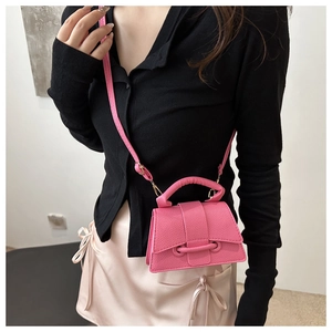 Detail of a bright pink mini crossbody bag with litchi grain leather and a stylish top handle