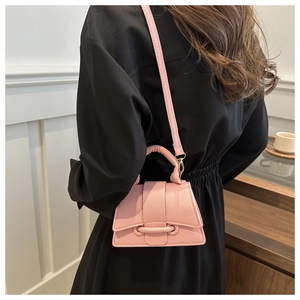 Detail shot of a pink mini crossbody bag in lychee pattern leather worn by a model