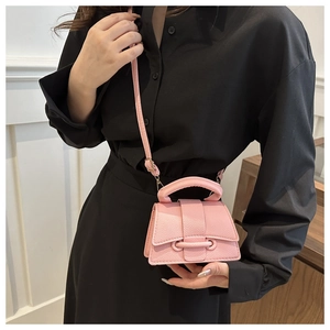 Detail of pink lychee textured mini crossbody bag worn by model on black dress