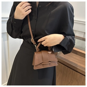 Detail of a brown lychee pattern leather mini handbag with gold hardware and trapezoid design