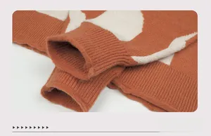 Dettaglio macro del polsino a coste e motivo jacquard geometrico su maglione arancione