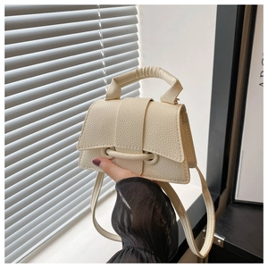 Detail view of cream lychee-textured mini crossbody bag with top handle and strap