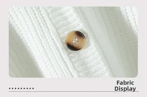 Close-up of white ribbed knit fabric texture and brown tortoiseshell button detail