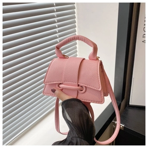 Detailed close-up of pink litchi grain leather mini square bag with unique strap closure