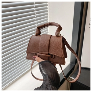 Close-up of brown litchi pattern leather handbag with thick cylindrical handle