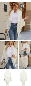 Detail of knit cape with faux fur collar and fringe hem on a beige winter poncho