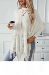 Detail of white hollow-out knit shawl featuring intricate mesh texture and fringed hemline
