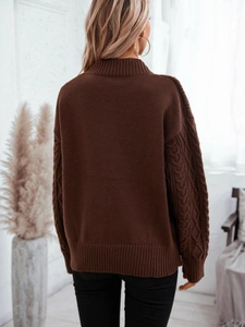 Loose dark brown cable knit turtleneck sweater for women with ribbed hem in cozy setting