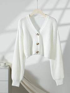 Detail of white V-neck cropped knit cardigan with brown buttons and puff sleeves