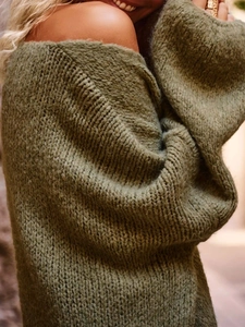 Detail eines olivgrünen Grobstrickpullovers mit schwerer Textur und Oversize-Schulterschnitt