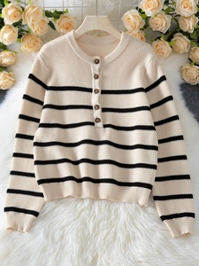 Close-up of striped knit sweater featuring a round neck and five brown wooden buttons