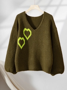 Dunkelgrüner V-Ausschnitt Pullover mit gelben Herzen auf einem Holzkleiderbügel