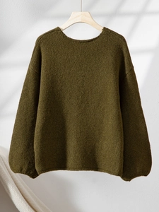 Detail eines moosgrünen V-Ausschnitt Strickpullovers mit Herzmuster und weichem Stoff