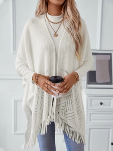 Elegant white hollow knit poncho with fringe details for a stylish autumn look