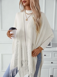 Detail of white hollow-out knit shawl featuring bohemian tassel hem and intricate patterns
