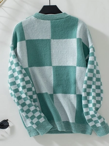 Detail of green and white checkered knit sweater with ribbed cuffs and neckline