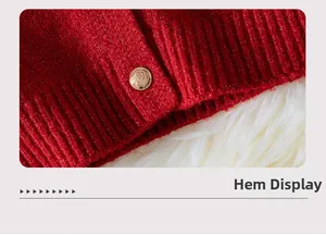 Detail of red ribbed knit hem featuring an elegant embossed gold metal button