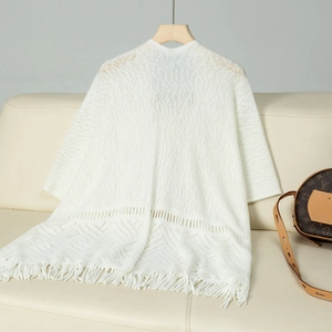 Close-up of white hollow knit shawl showing delicate crochet patterns and soft tassels