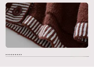 Detail of loose knit cardigan hem showing brown fabric and black striped ribbing