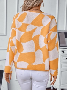 Back view of woman in orange and white geometric knit sweater with rolled edges