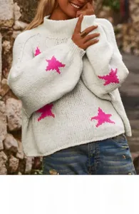 Detail of white knit sweater featuring pink star pattern and loose lantern sleeves