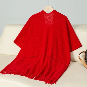 Close-up of red knit poncho featuring diamond hollow patterns and long fringe tassels