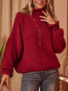 Detail of red oversized turtleneck sweater featuring thick knit texture and ribbed cuffs