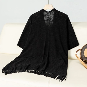 Detail of black hollow knit shawl featuring elegant fringe tassels and airy texture