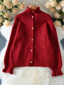 Detailed close-up of dark red cardigan featuring gold embossed buttons and ruffled cuffs