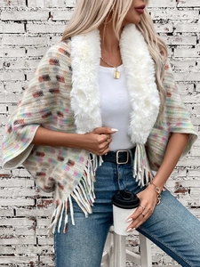 Detail of colorful knit shawl with premium faux fur collar and fringe hem outdoors