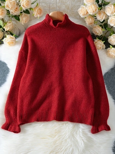Detail of red knit sweater featuring stylish ruffled cuffs and warm ribbed turtle neck design