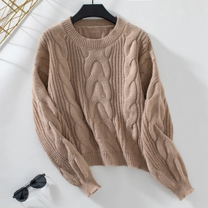 Detailed cable knit texture of a khaki oversized crewneck sweater with fashion accessories