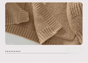 Detailed macro view of the thick knit texture and ribbed hem on a warm camel cardigan