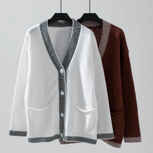 Detailed view of knitted cardigan buttons with contrasting stripe edges and side pockets