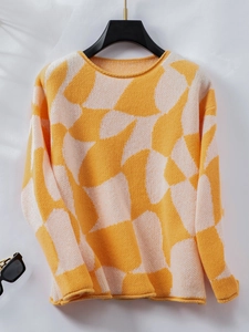 Detail of round neck knitted sweater featuring bold yellow and white geometric patterns