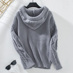 Detail of grey cable-knit hooded cardigan featuring ribbed cuffs and thick wool texture