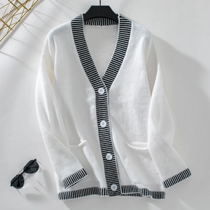 Detail of V-neck white knit cardigan with black stripes and single-breasted white buttons