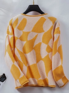 Detail of color-block knit sweater featuring yellow and beige panels with rolled edges
