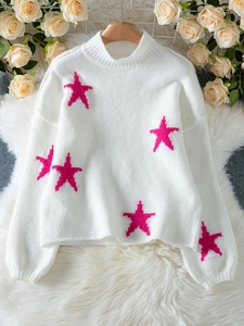 Close-up of white knit sweater featuring pink star patterns and soft ribbed texture
