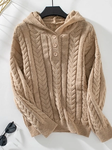 Flat lay of chunky cable knit hooded sweater with vintage buttons and khaki texture